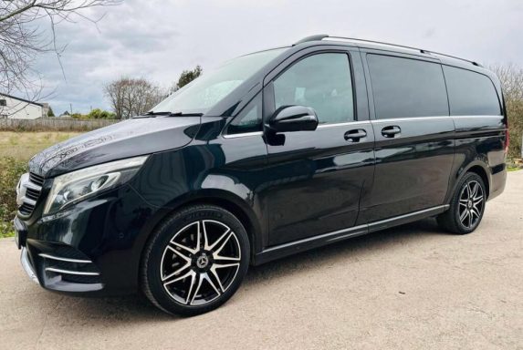 Black Mercedes van with sleek design and alloy wheels, parked on a gravel surface.